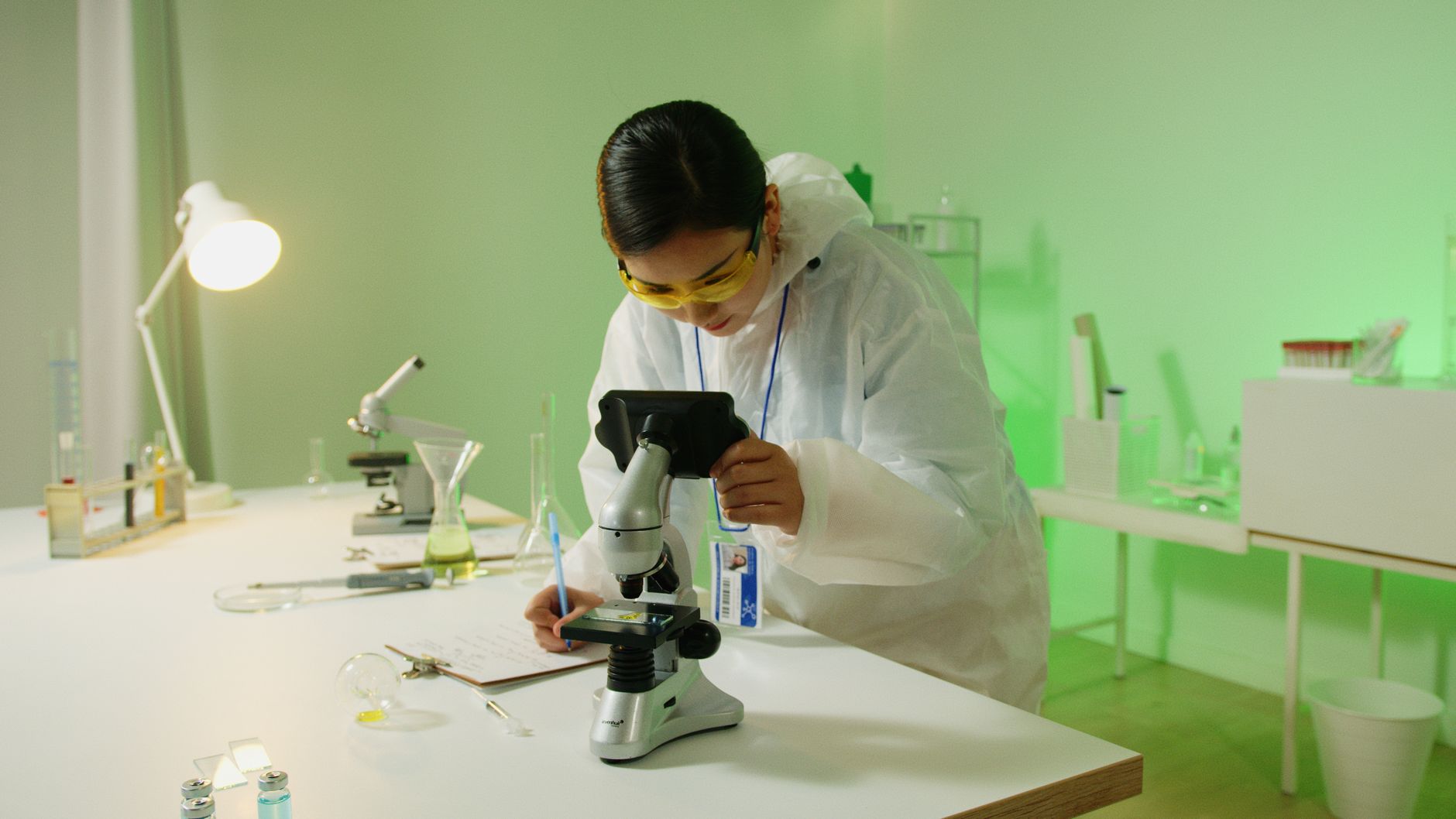 scientist working in modern laboratory with microscope and scientific equipment surrounded by research papers and data displays