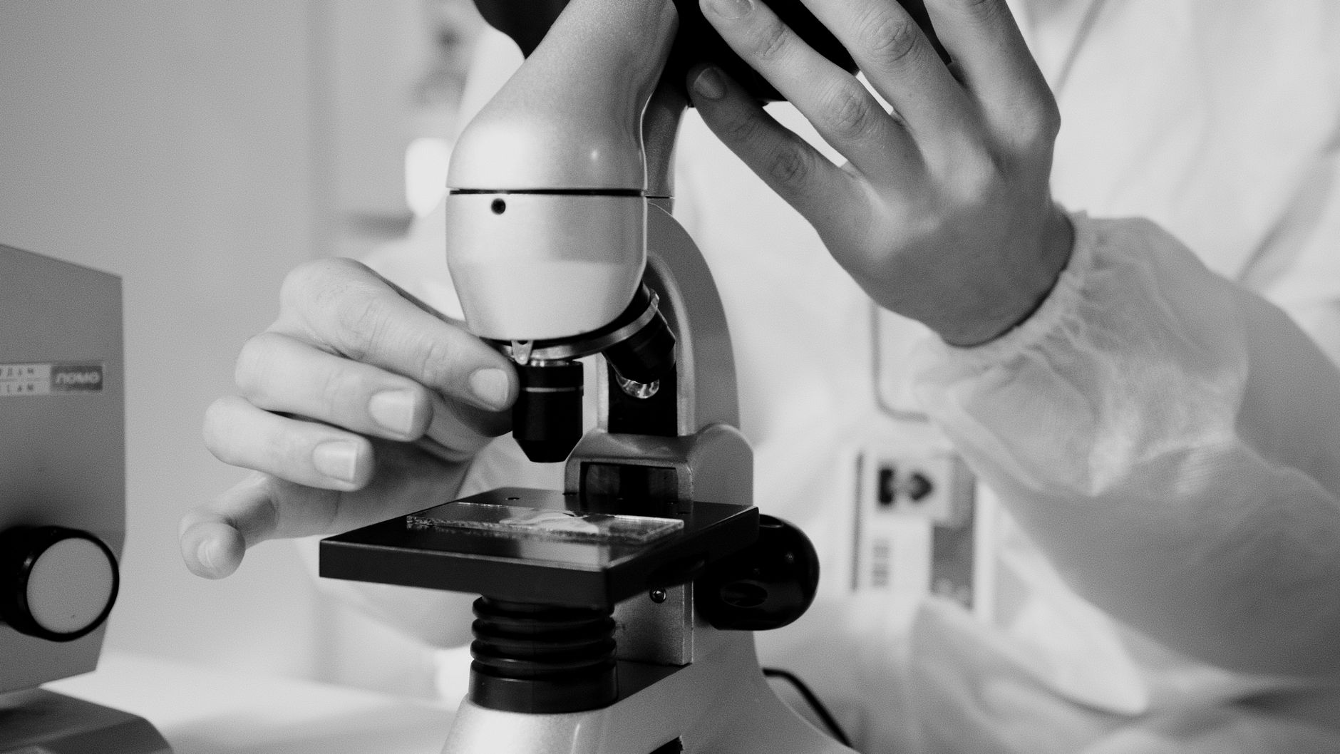 researcher examining fossil bone under microscope dark laboratory close up detail