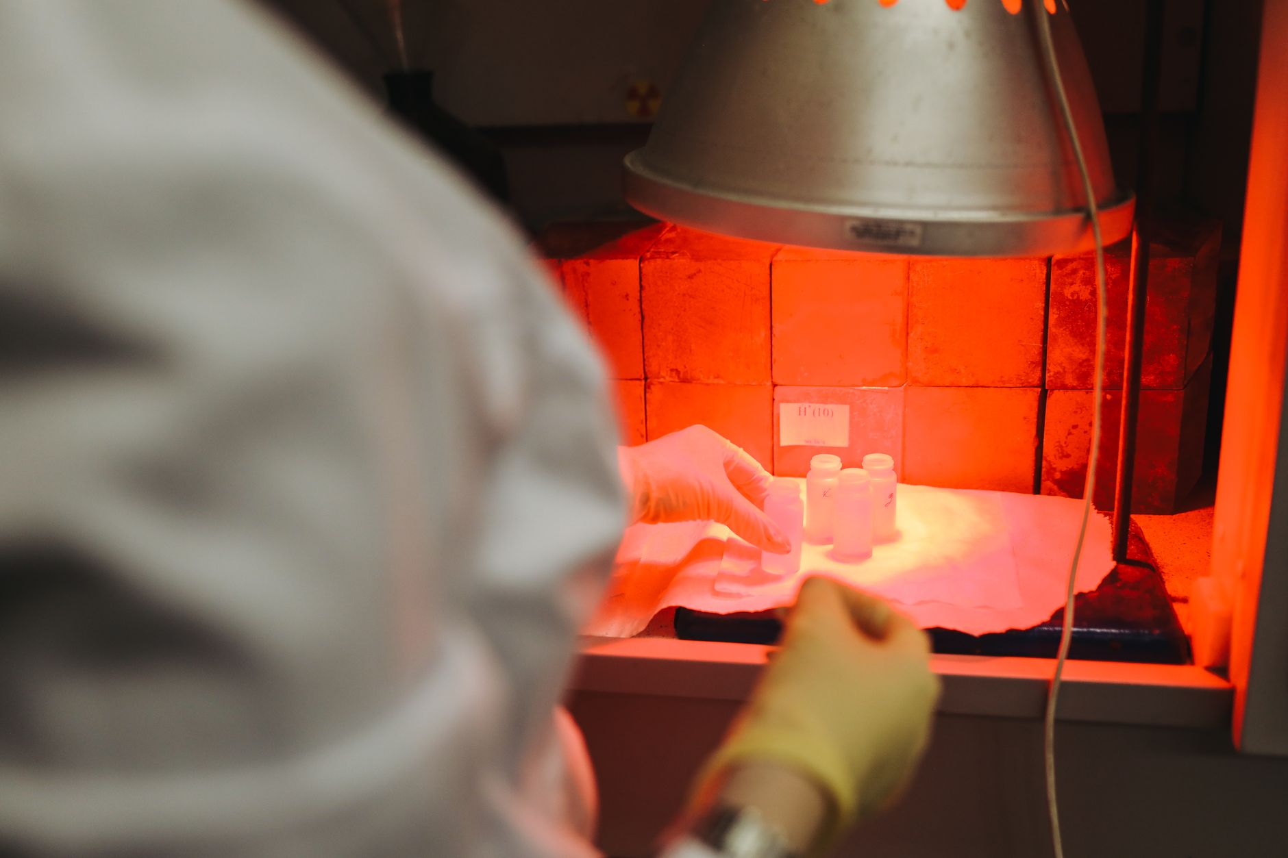 scientist examining glowing bacteriophage samples in dark laboratory blue light