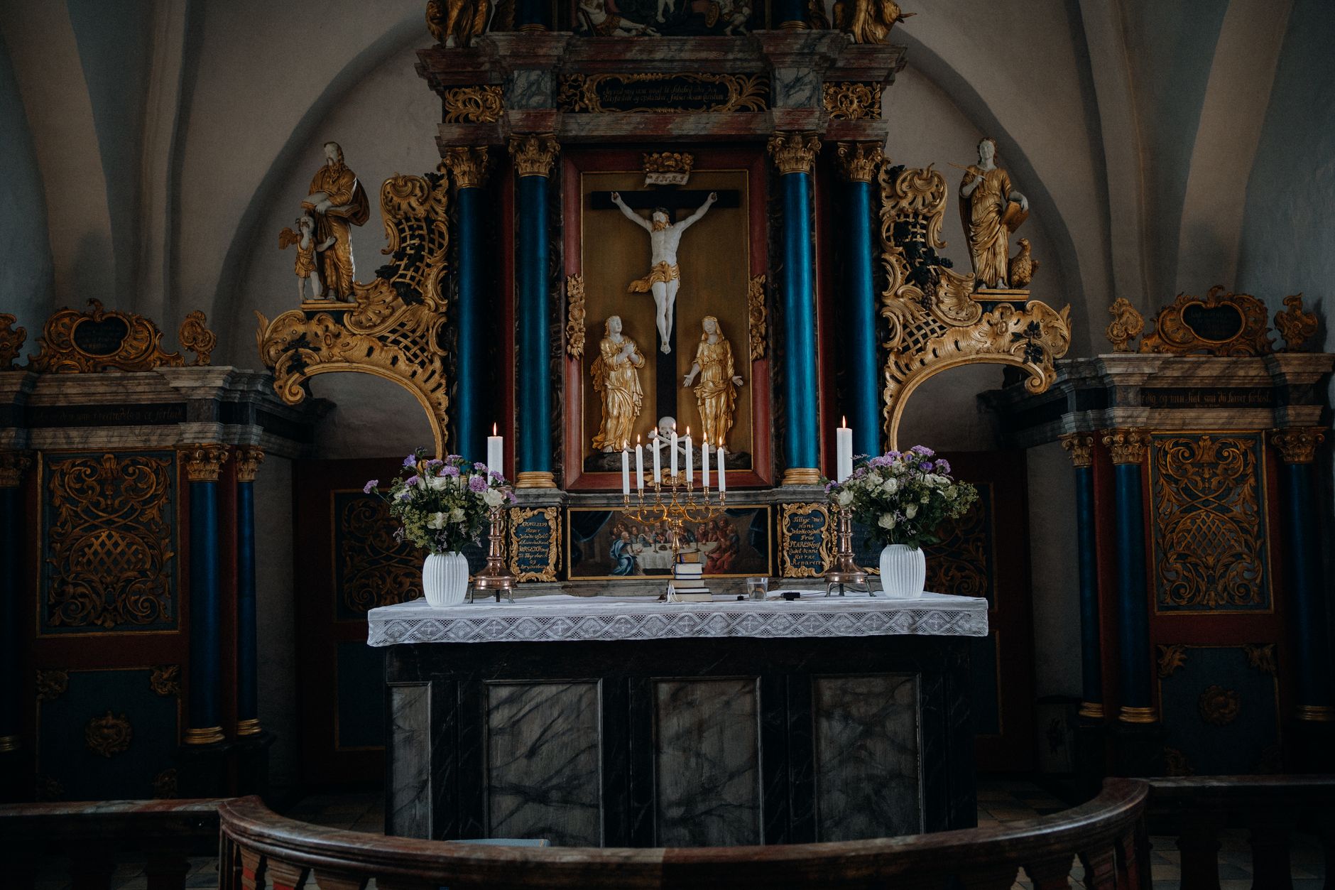 ornate baroque wooden altar with golden decorative elements and religious sculptures in spanish church interior with dramatic candlelight