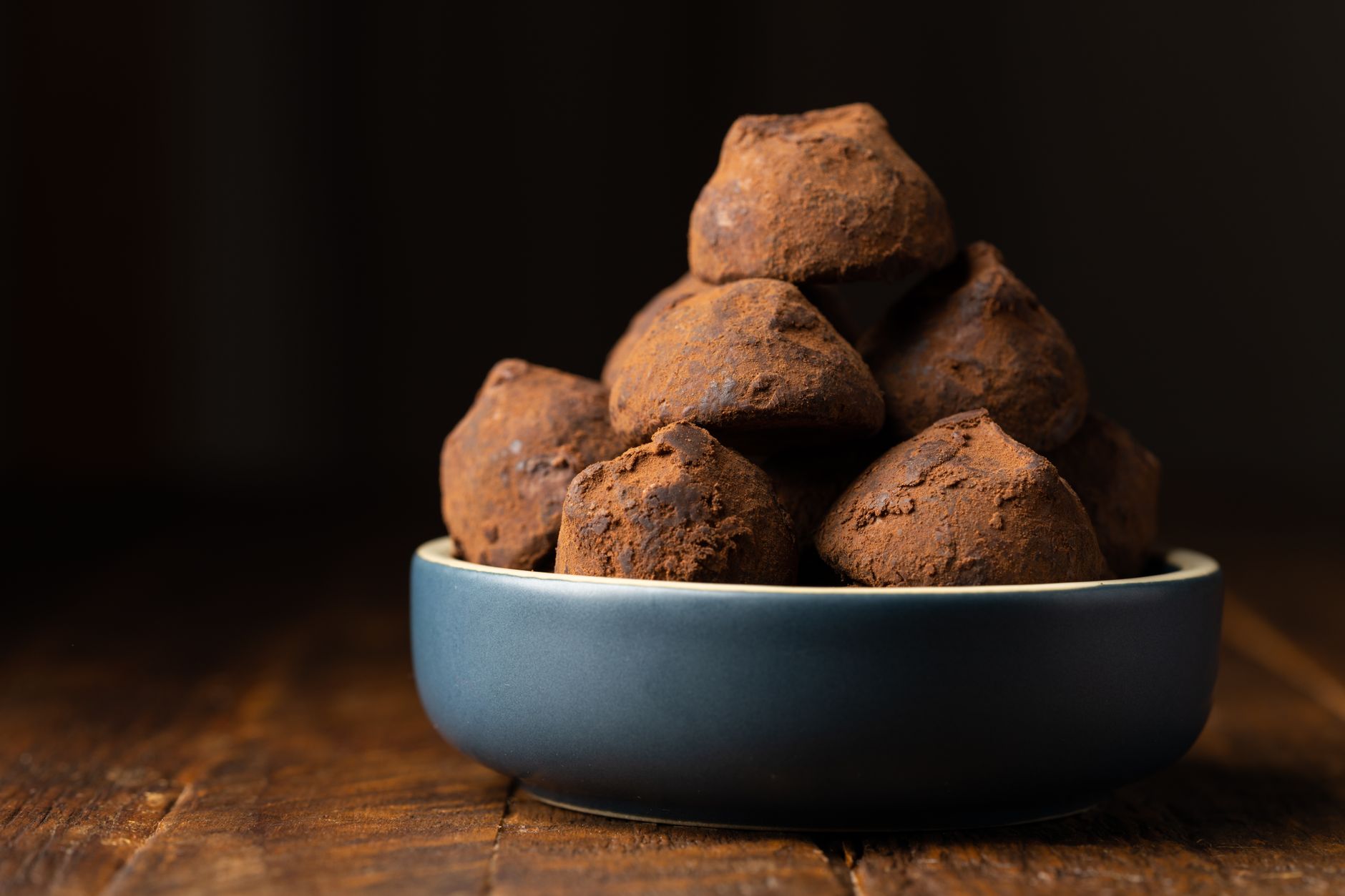close-up of fresh black truffles on rustic wooden table with soil texture and knife