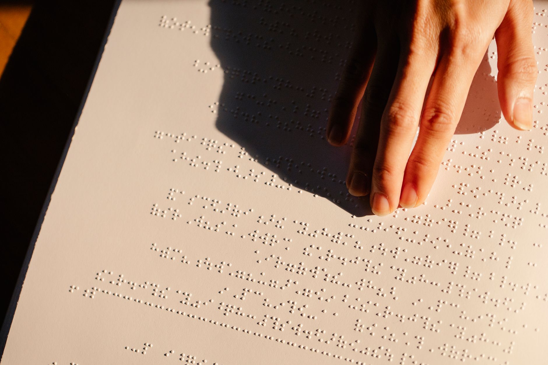 close-up hand tracing embossed braille dots on paper texture
