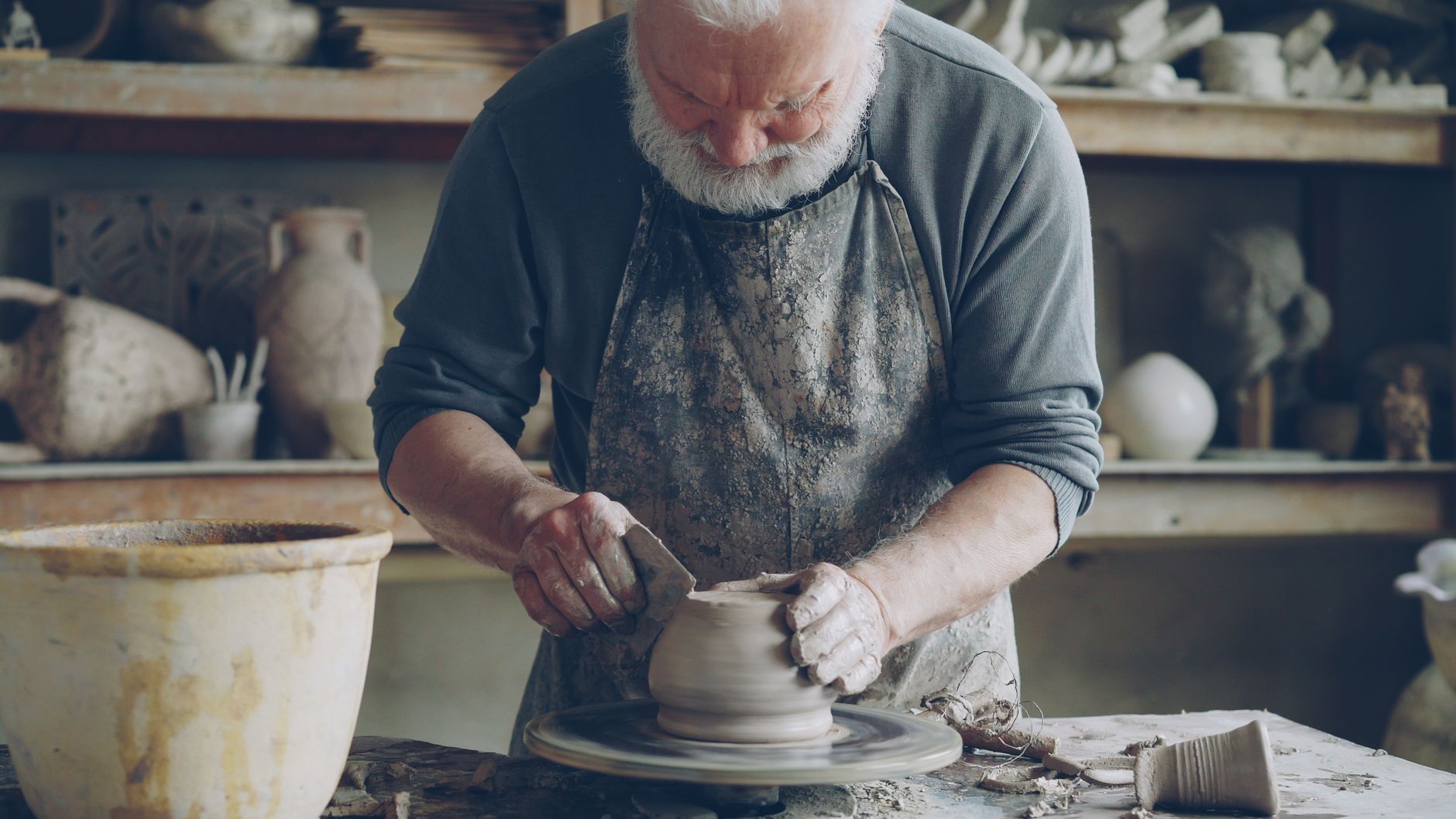 elderly artisan shaping a wooden threshing sledge trillo in a traditional Spanish barn workshop
