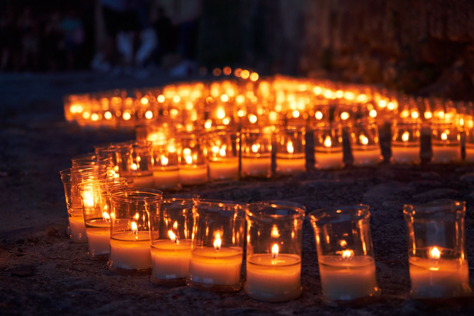 traditional Spanish village festival at dawn, folk dancers and candles in a meadow, warm golden light