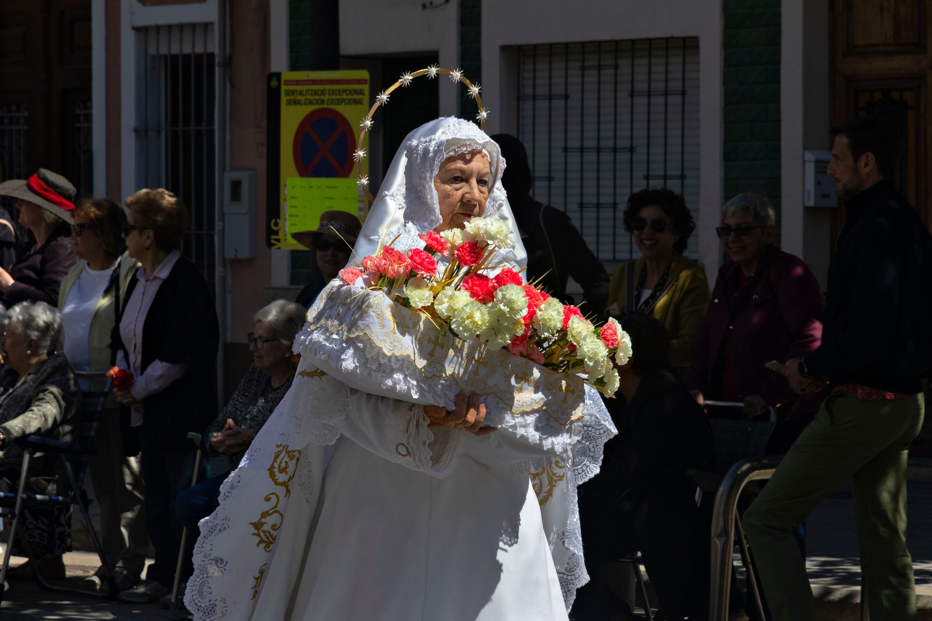 close up of woman wearing traditional Manchego embroidered kerchief and dress carrying flowers in procession