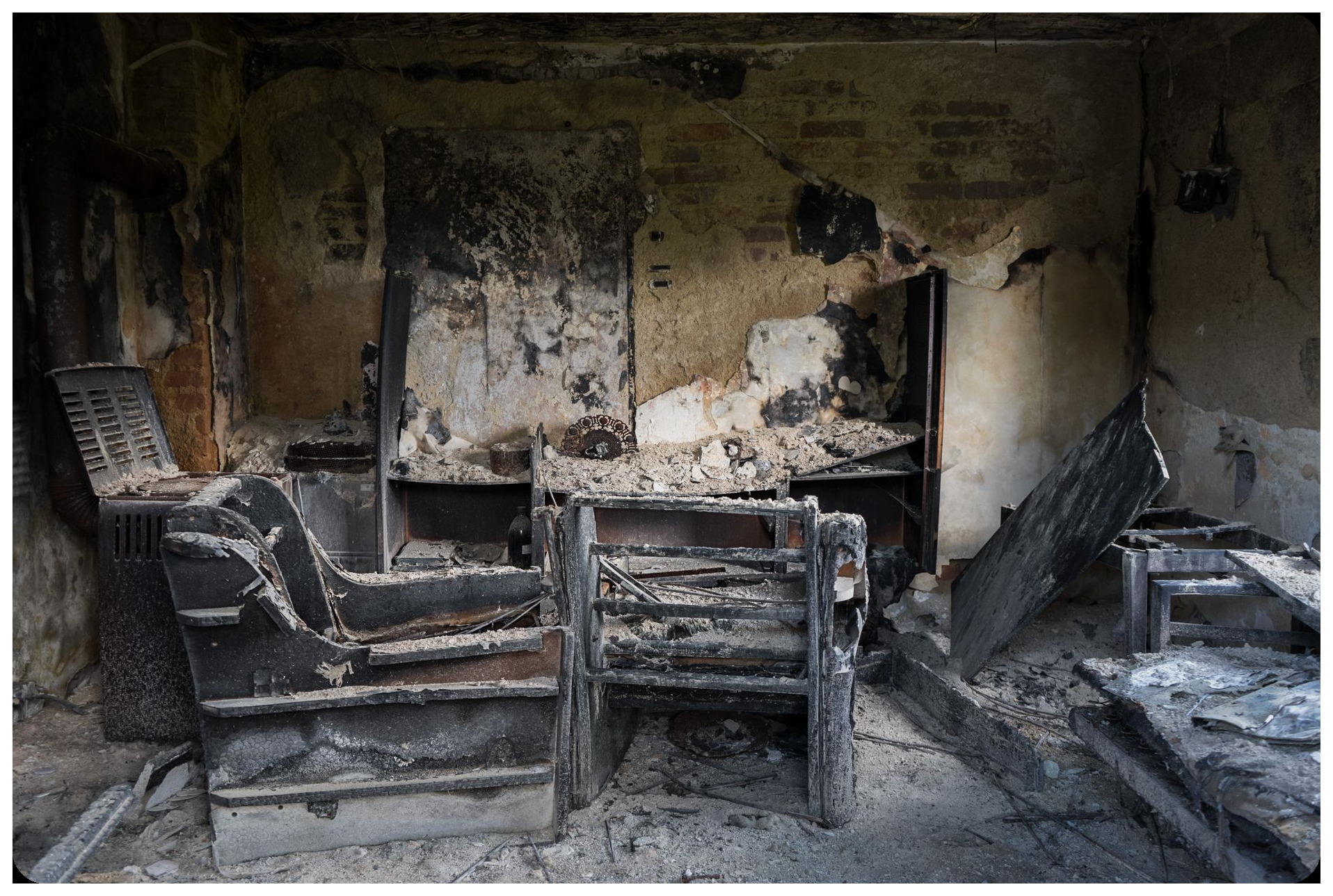 charred wooden beams and fire-blackened stone walls of ancient iberian dwelling exposed during excavation showing interior compartments