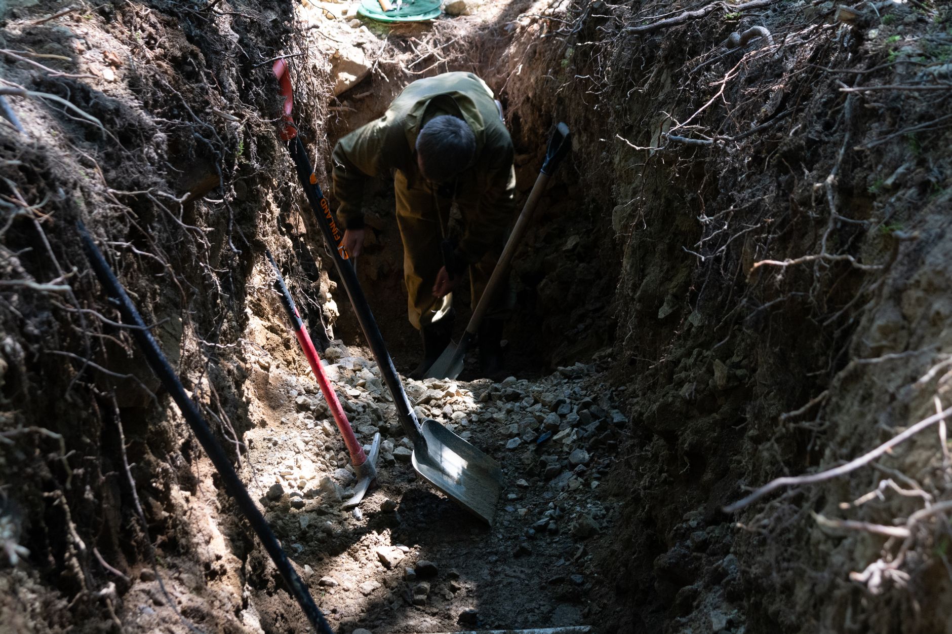 archaeologist carefully brushing dirt from ancient artifact excavation trench closeup