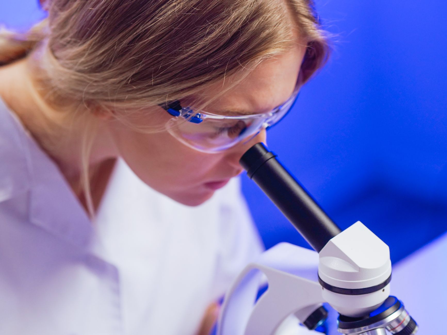 paleoanthropologist examining ancient bone fragment under microscope in laboratory