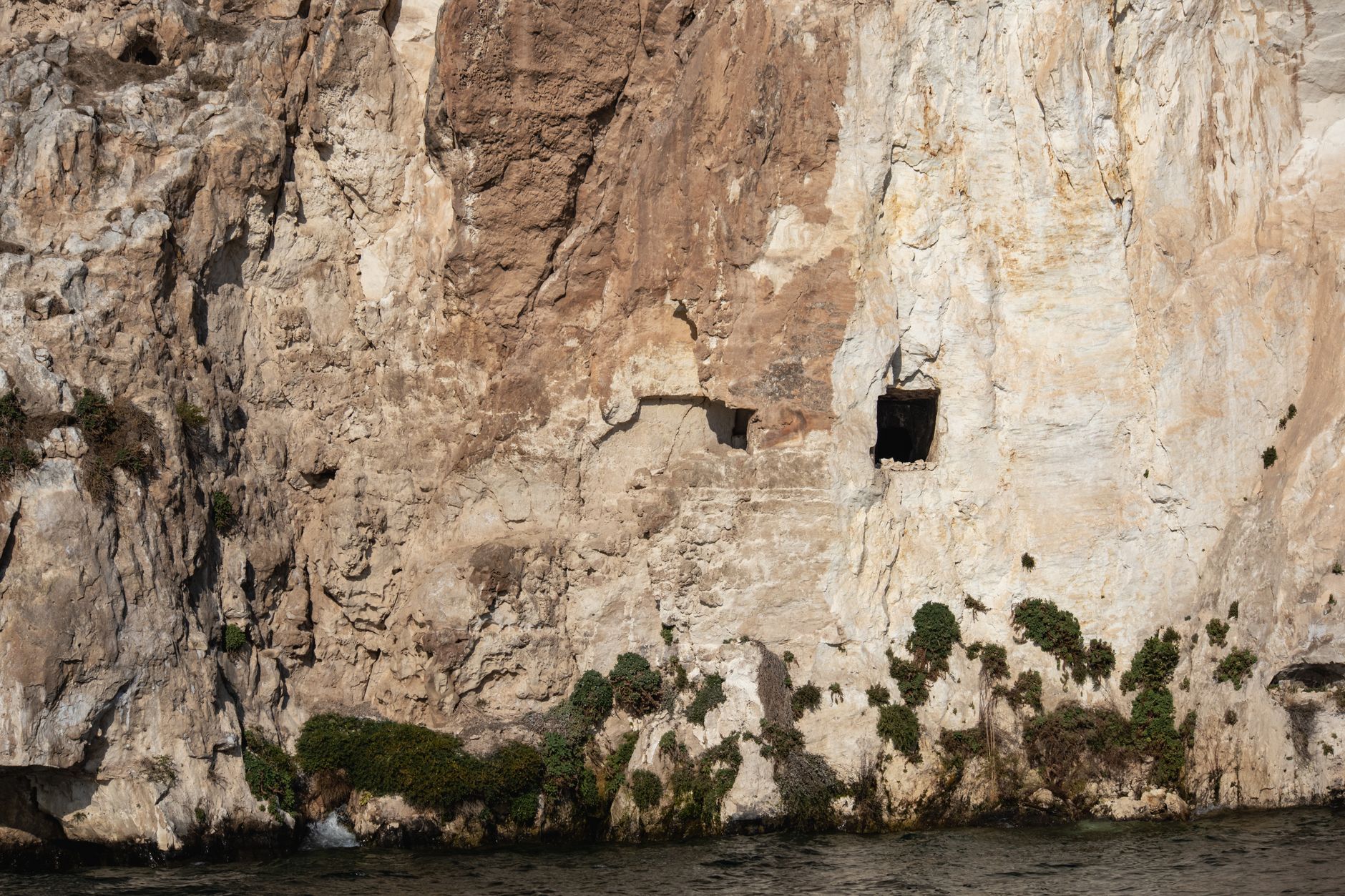 prehistoric cave excavation site mediterranean cliffside dramatic golden sunset light